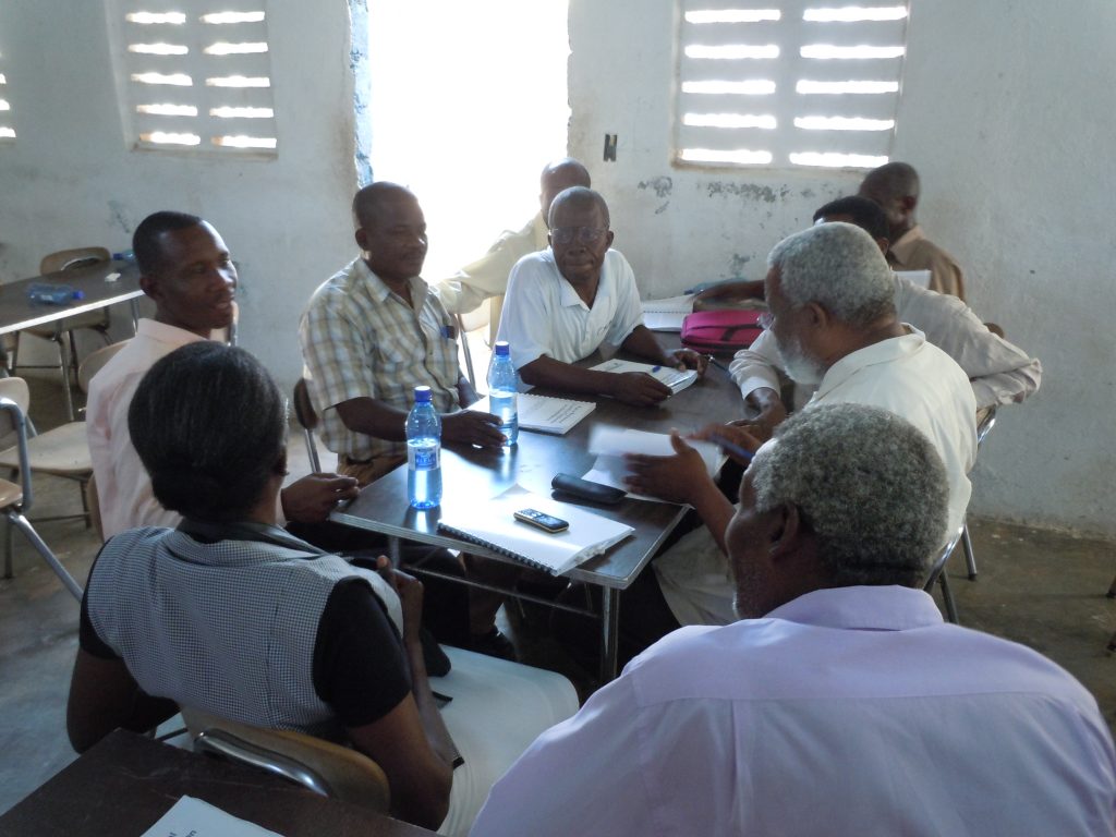 Pastors lean into a small-group discussion around a table of workbooks