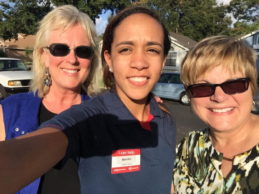 Two outreach team members and a new friend they met smile together in warm evening light.