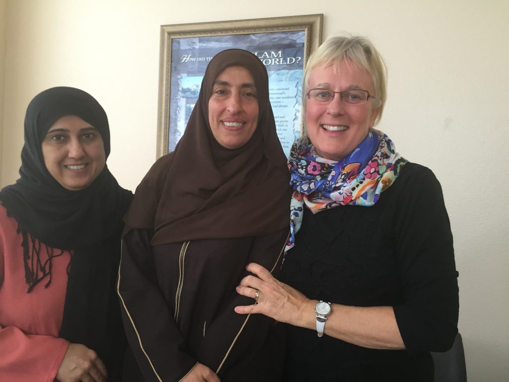 Three women stand close together, smiling, after a friendship visit during 40 Days of Love.