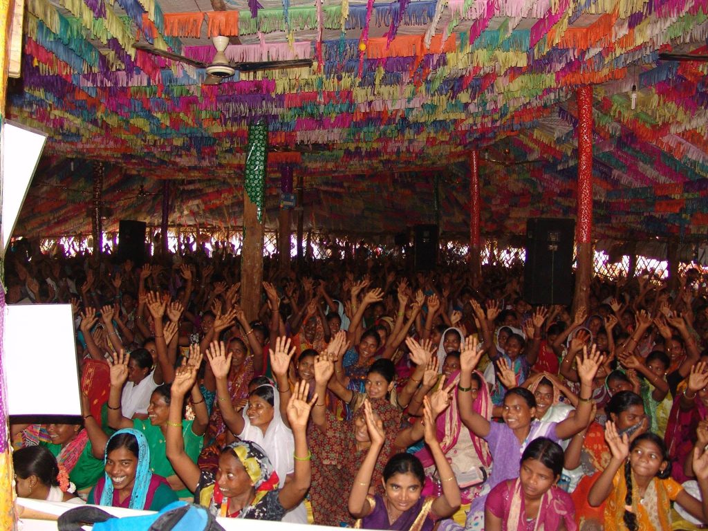 A large evangelistic meeting with a crowd worshipping