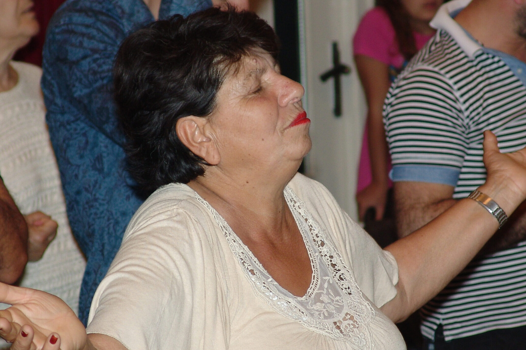 A woman stands mid-worship with eyes closed and palms open