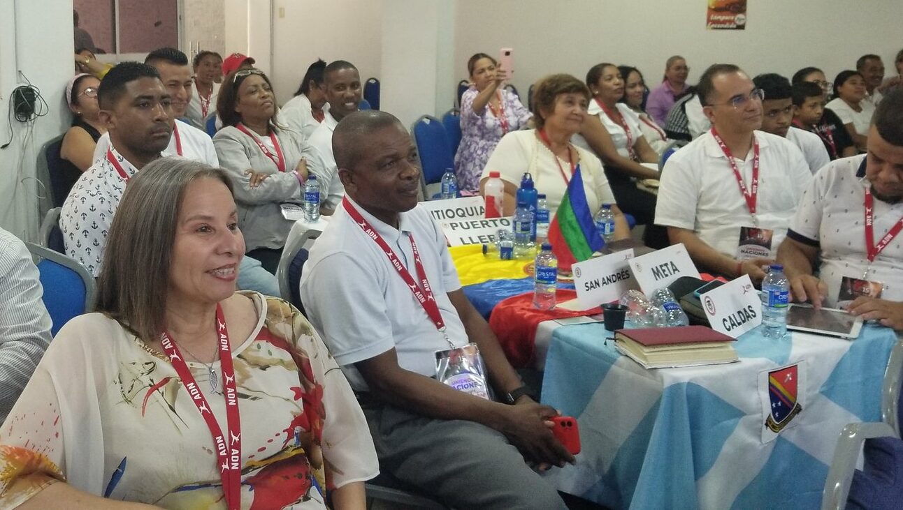 Ministry leaders from regions across Colombia sit together at a gathering, with department name cards on the tables.